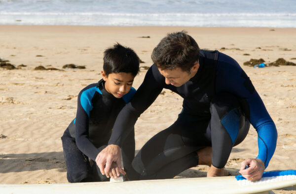 Man with boy and surfboard on beach